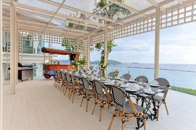 a long table and chairs on a patio with a piano at Villa W Collection in Nai Harn Beach