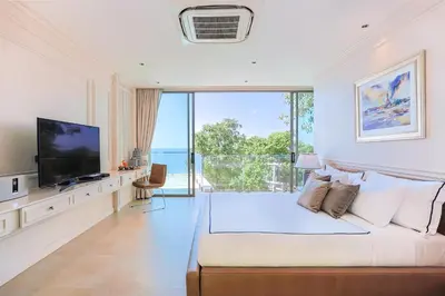 a white bedroom with a large bed and a television at Villa W Collection in Nai Harn Beach