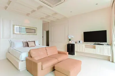 a bedroom with a bed and a chair and a television at Villa W Collection in Nai Harn Beach