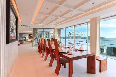 a dining room with a table and chairs and windows at Villa W Collection in Nai Harn Beach