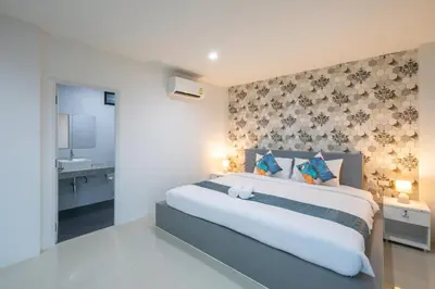 a bedroom with a large bed with a wall at Chanakarn Pool Access Rawai in Rawai Beach