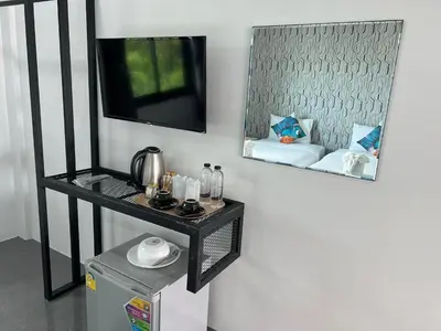 a mirror on a wall with a table and a tv at Chanakarn Pool Access Rawai in Rawai Beach