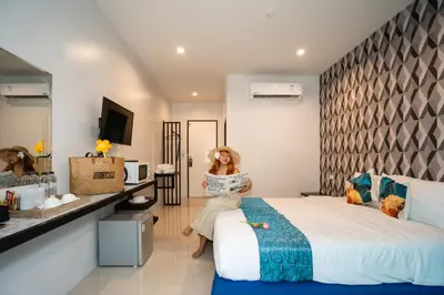 a woman is sitting on a bed in a hotel room at Chanakarn Pool Access Rawai in Rawai Beach