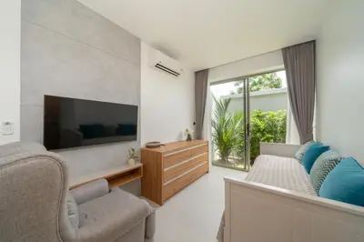 a living room with a flat screen tv and chairs at Villa private swimming pool and garden in Phuket Town
