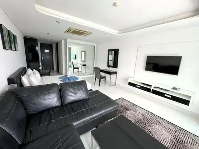 a living room with a black leather couch and a flat screen tv at Private sea view studio at Twin Sands in Patong Beach