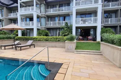 a hotel with a swimming pool in front of a building at Allamanda Laguna 2 BR c выходом к бассейну in Phuket Town