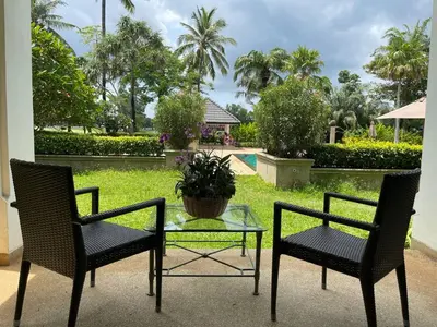 two chairs and a table with a potted plant on a patio at Allamanda Laguna 2 BR c выходом к бассейну in Phuket Town