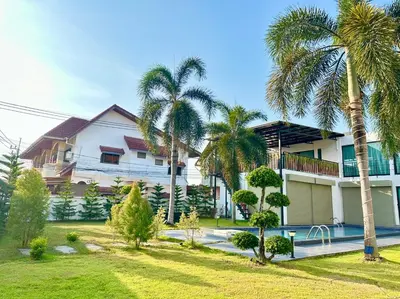 a house with palm trees in front of it at The White House Kamala Phuket in Kamala Beach