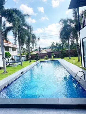 a large swimming pool with palm trees in a yard at The White House Kamala Phuket in Kamala Beach