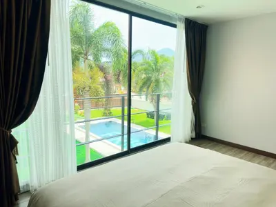 a bedroom with a large window with a view of a pool at The White House Kamala Phuket in Kamala Beach