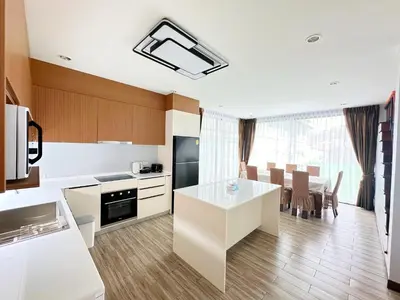 a kitchen with a white table and a dining room at The White House Kamala Phuket in Kamala Beach