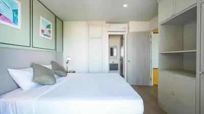 a bedroom with a large white bed and shelves at DLUX Condominium Chalong Phuket in Ban Klang