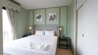 a bedroom with two beds and two pictures on the wall at DLUX Condominium Chalong Phuket in Ban Klang