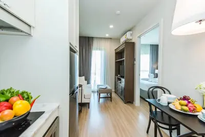 a kitchen and living room with a table with fruits on it at DLUX Condominium Chalong Phuket in Ban Klang