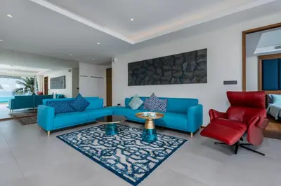 a living room with blue couches and red chairs at WEG Elite Beachfront in Phuket Town
