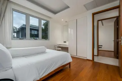 a white bedroom with a bed and a window at WEG Elite Beachfront in Phuket Town