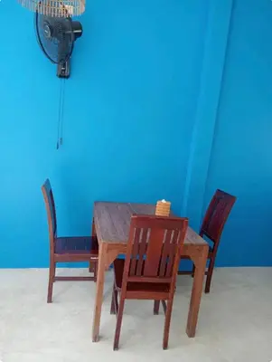 a wooden table with four chairs and a blue wall at Rapina House in Mai Khao Beach