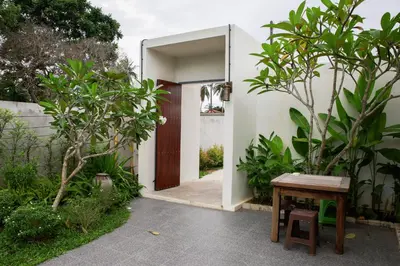 a door leading into a garden with a wooden table at Rapina House in Mai Khao Beach