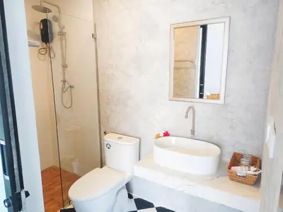 a bathroom with a toilet and a sink and a mirror at Rapina House in Mai Khao Beach