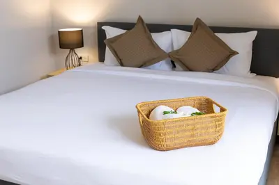 a basket of towels is sitting on a bed at Rapina House in Mai Khao Beach