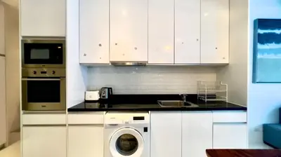 a kitchen with white cabinets and a washing machine at Kamala Falls Seaview 2 bedroom in Kamala Beach