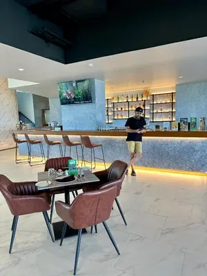 a man standing in a restaurant with tables and chairs at Duplex in a 5 star hotel La Vita in Phuket Town