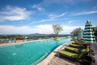 a large swimming pool with lounge chairs and umbrellas at 2 bdr Apartment Calypso Garden NaiHarn Beach by Capital Pro CGC-310 in Rawai Beach