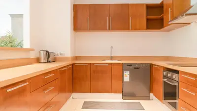 a kitchen with wooden cabinets and a stainless steel dishwasher at Recently renovated 3BR apartment near Layan Beach in Phuket Town