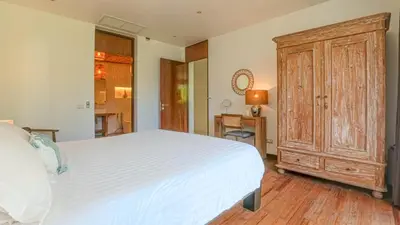 a bedroom with a large white bed and a wooden cabinet at Recently renovated 3BR apartment near Layan Beach in Phuket Town