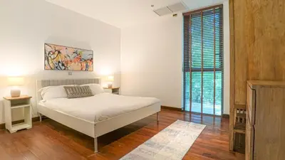 a white bedroom with a bed and a large window at Recently renovated 3BR apartment near Layan Beach in Phuket Town