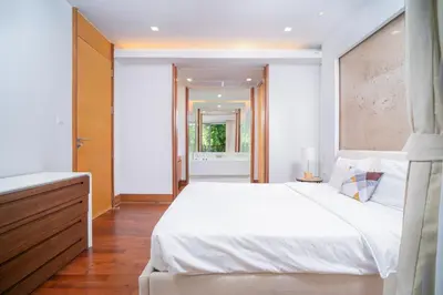 a bedroom with a large white bed and a hallway at Modern Beachfront Apartment Naithon Beach in Nai Thon Beach