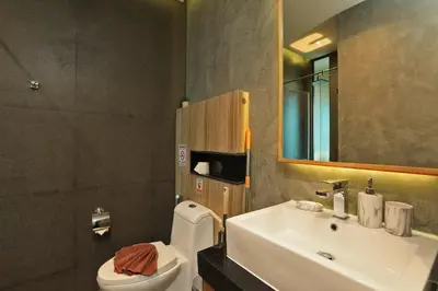 a bathroom with a sink and a toilet and a mirror at 1bdr Apartment near NaiHarn beach by Capital Pro in Phuket Town