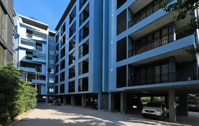 a blue apartment building with a car parked in front at 1bdr Apartment near NaiHarn beach by Capital Pro in Phuket Town