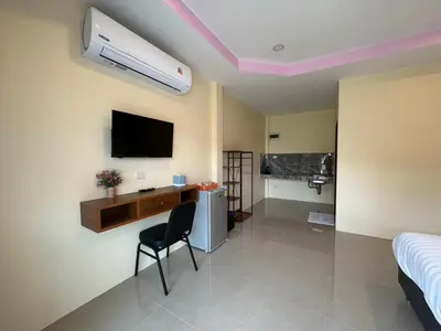 a room with a bed and a desk and a tv at พัชรี รีสอร์ท ภูเก็ต Patcharee Resort Phuket in Phuket Town