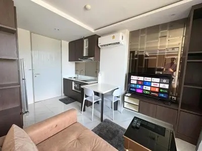a living room with a couch and a table and a kitchen at Top floor apartment at Aristo by Lofty in Surin Beach