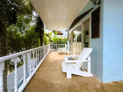 a pair of white chairs sitting on the porch of a house at Mountain View Villa Kamala in Kamala Beach