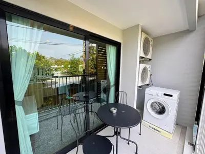 a balcony with two tables and a washing machine at The Title VH Rawai by Beringela in Phuket Town