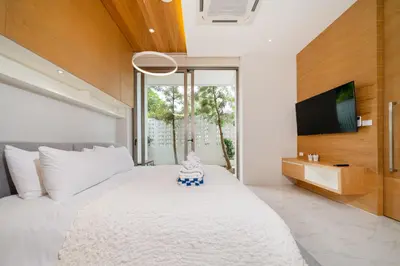 a bedroom with a large white bed and a tv at Andaman Villa 15 minutes from Bangtao Beach in Phuket Town