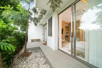an external view of a house with glass doors and a garden at Andaman Villa 15 minutes from Bangtao Beach in Phuket Town
