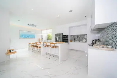 a kitchen with white cabinets and a bar with stools at Andaman Villa 15 minutes from Bangtao Beach in Phuket Town