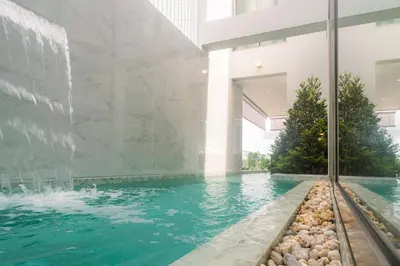 a swimming pool with a waterfall in a building at Andaman Villa 15 minutes from Bangtao Beach in Phuket Town