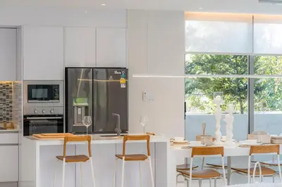 a kitchen with white cabinets and a table with chairs at Andaman Villa 15 minutes from Bangtao Beach in Phuket Town