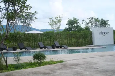 a swimming pool with lounge chairs and an umbrella at Alisse Stay Phuket Layan in Phuket Town
