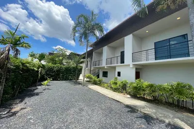 a white house with a driveway and palm trees at Alisse Stay Phuket Layan in Phuket Town