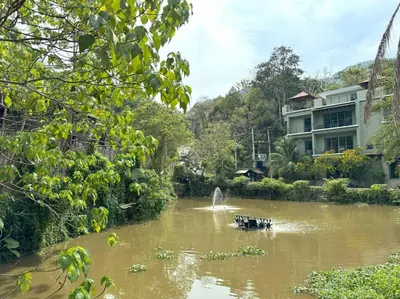 a boat in a river in front of a building at Kamala townhome with sea view terrace & pool in Kamala Beach