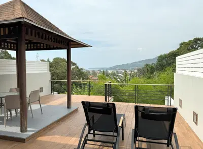 a deck with chairs and a gazebo at Kamala townhome with sea view terrace & pool in Kamala Beach
