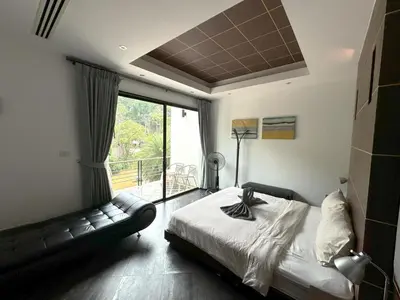 a bedroom with a bed and a couch and a window at Kamala townhome with sea view terrace & pool in Kamala Beach
