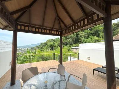 a patio with a table and chairs on a deck at Kamala townhome with sea view terrace & pool in Kamala Beach