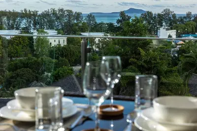 a table with glasses and plates on it with a view at C260 Beach And Town, Modern Big Apartment in Phuket Town
