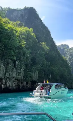 a boat in the water next to a mountain at La Depa PP House in Phi Phi Don
